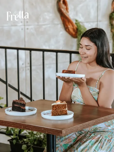 Clienta en la terraza con torta de chocolate y carrot cake